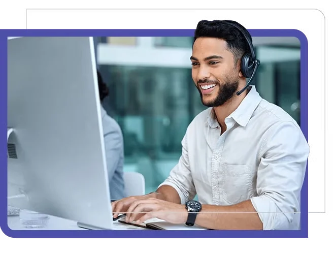 Young man, smiling at computer screen with headphones.